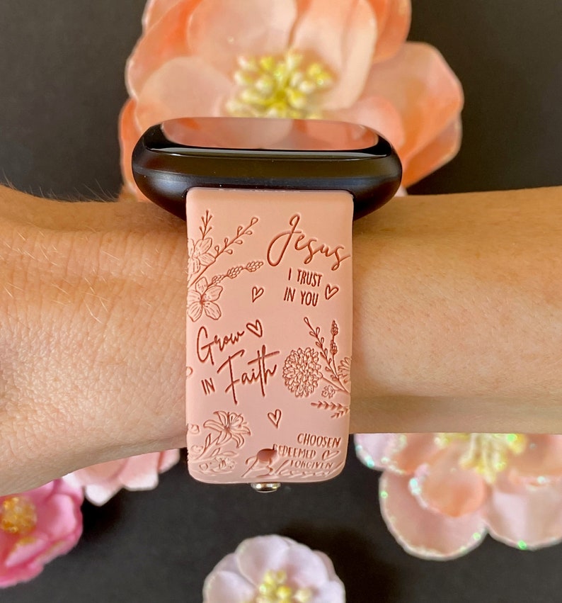 May include: A pink silicone watch band with a floral design and the text "Grow in Faith" and "Jesus I Trust in You".