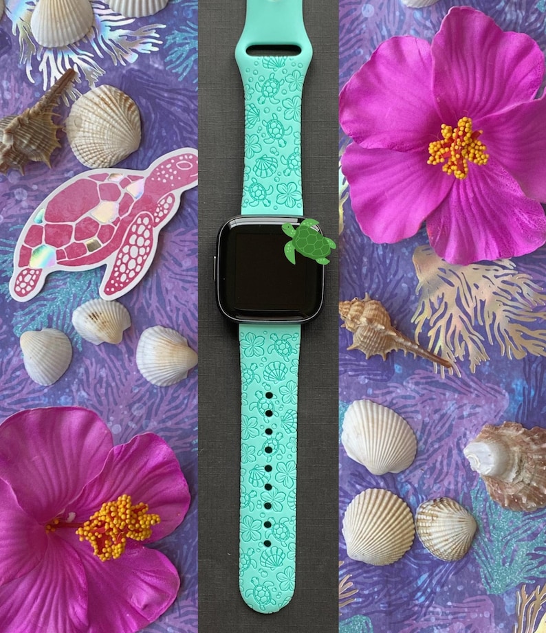 Pu&ograve; includere: Un cinturino per orologio in silicone blu turchese con un design a forma di tartaruga marina e conchiglie. Il cinturino &egrave; mostrato su uno sfondo nero.