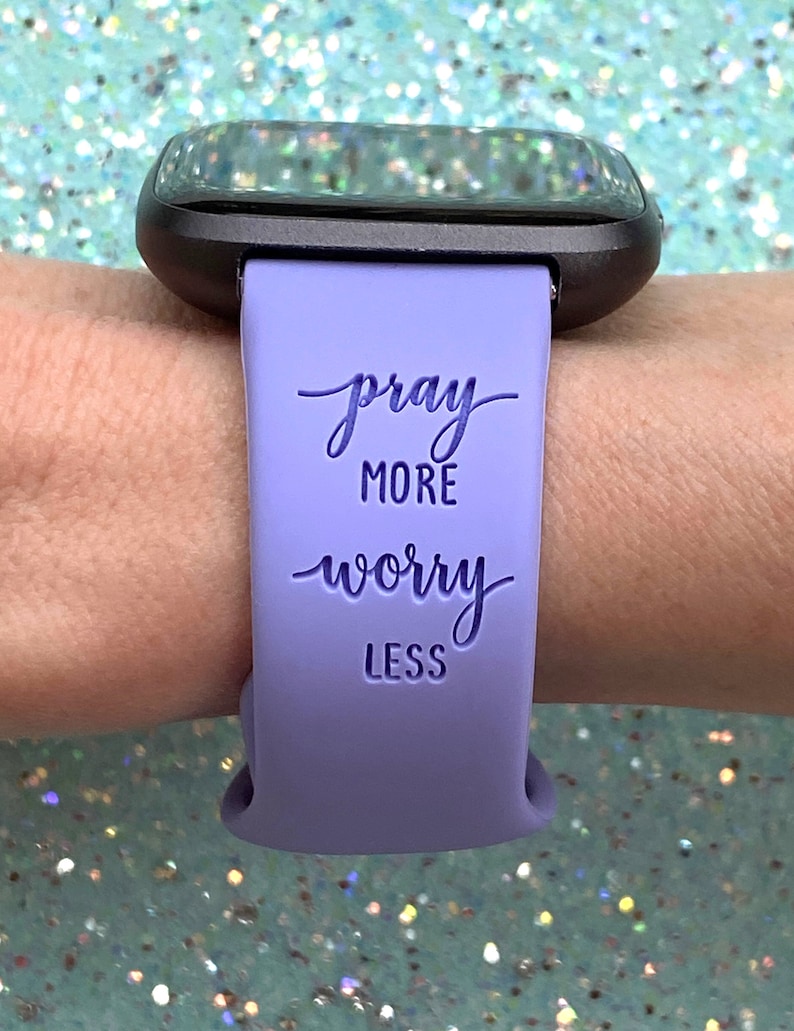 May include: A lavender silicone watch band with the text "pray more worry less" printed on it.