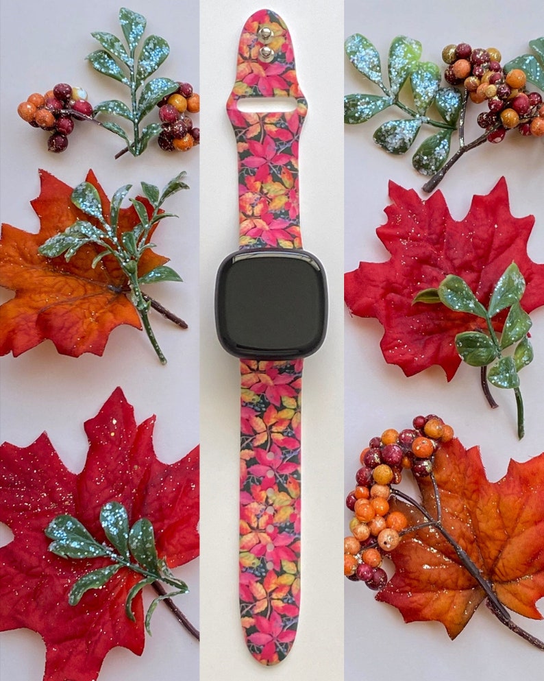 May include: A pink and black watch band with a fall leaf pattern. The band is made of silicone and has a black watch face.