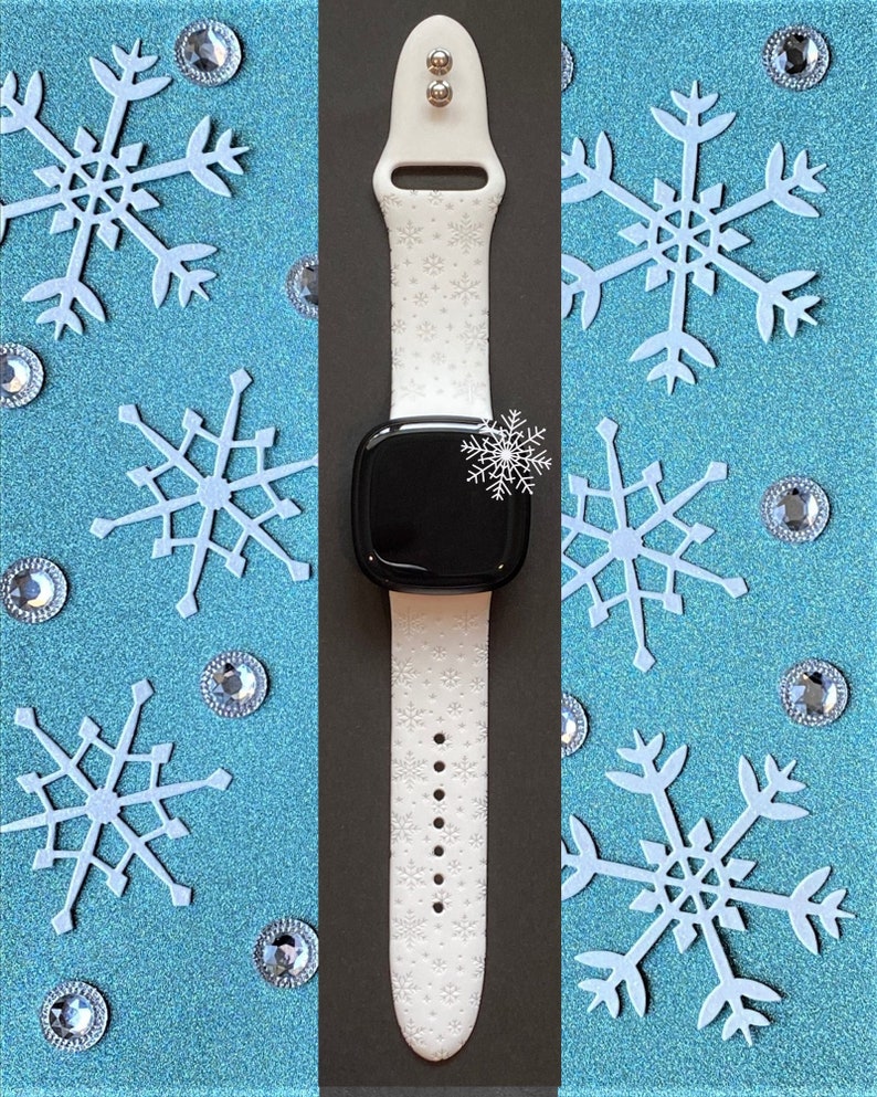 Pu&ograve; includere: Cinturino bianco per smartwatch con motivo a fiocco di neve. Il cinturino &egrave; in silicone e ha un quadrante nero.