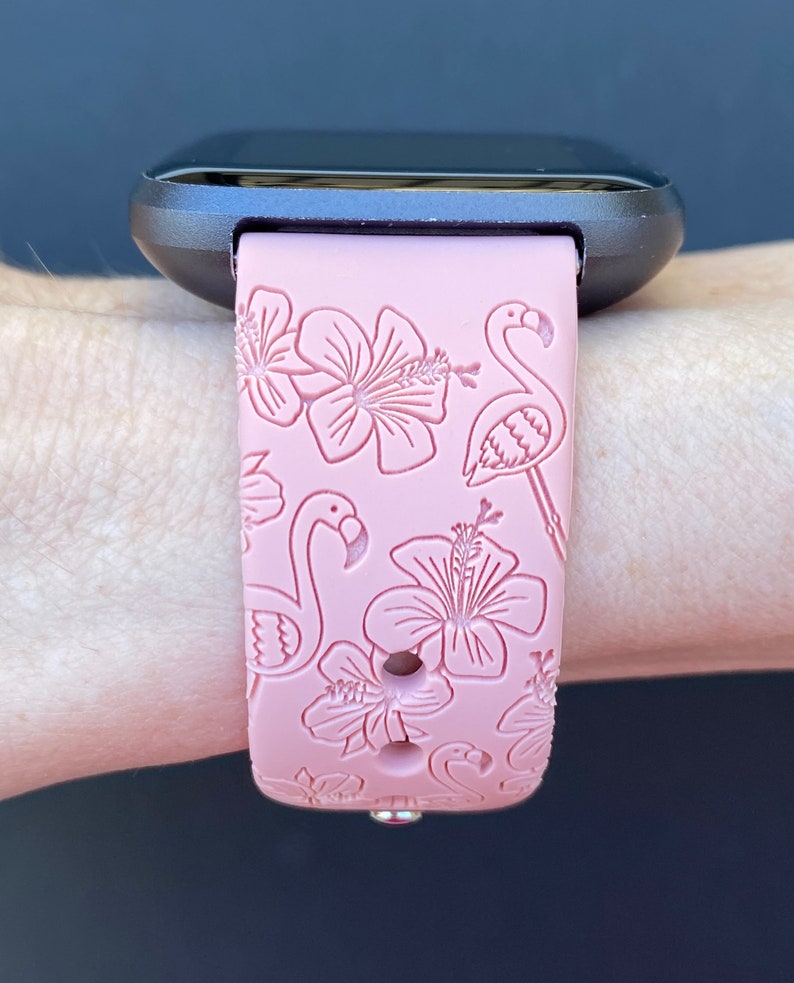 May include: A pink silicone watch band with a flamingo and hibiscus flower design.