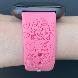 Peut inclure: Bracelet de montre en silicone rose avec un motif de couple de gnomes. Les gnomes tiennent un c&oelig;ur sur lequel est inscrit "Je t'aime". Le bracelet est d&eacute;cor&eacute; de c&oelig;urs.