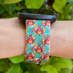 K&ouml;nnte beinhalten: Ein farbenfrohes Armband mit einem Muster aus Truth&auml;hnen und herbstlichen Designs. Das Armband ist aus Silikon und kompatibel mit Smartwatches.