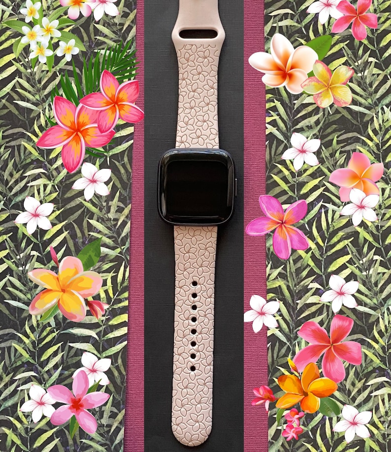 May include: A pink silicone watch band with a floral pattern. The band is designed for a smartwatch with a square face. The band is shown against a background of tropical flowers and leaves.