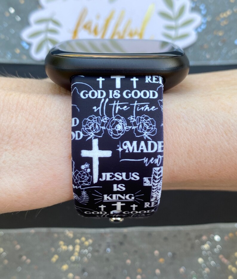 May include: Black and white watch band with a repeating pattern of crosses, flowers, and the text "God is good", "all the time", "Made new", "Jesus is King", and "God is good".