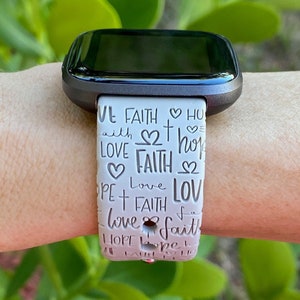 Puede incluir: Banda de reloj con estampado blanco y rosa con las palabras "Love Faith Hope" repetidas en un patr&oacute;n circular.