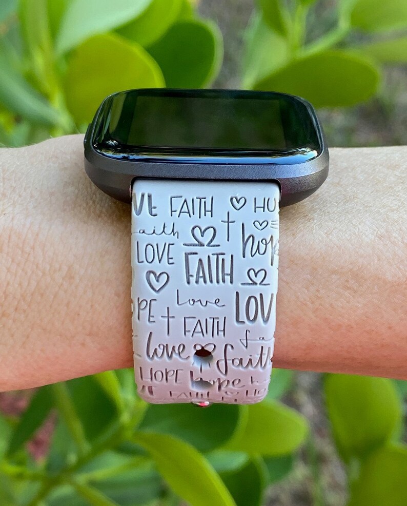 Puede incluir: Banda de reloj con estampado blanco y rosa con las palabras "Love Faith Hope" repetidas en un patr&oacute;n circular.