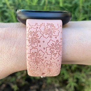 May include: A pink silicone watch band with a hibiscus flower pattern. The band is designed for a smartwatch.