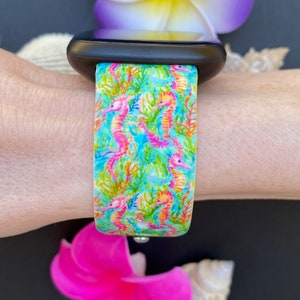 Puede incluir: Una correa de reloj azul turquesa y rosa con un patr&oacute;n de caballitos de mar. La correa est&aacute; hecha de silicona y es compatible con Apple Watch.