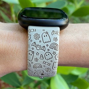 May include: A light gray smartwatch band with a Halloween-themed design. The band features ghosts, bats, stars, rainbows, candy, and the word "BOO!" in a white outline.