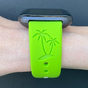 May include: A green silicone watch band with a palm tree design. The band has two small holes for ventilation.