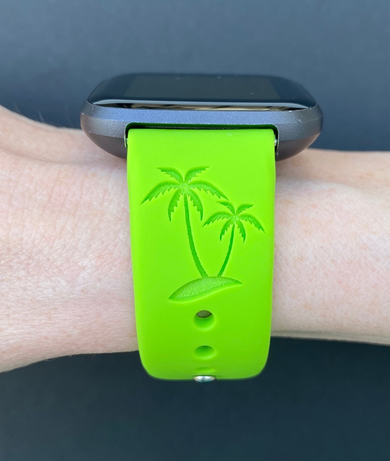 May include: A green silicone watch band with a palm tree design. The band has two small holes for ventilation.