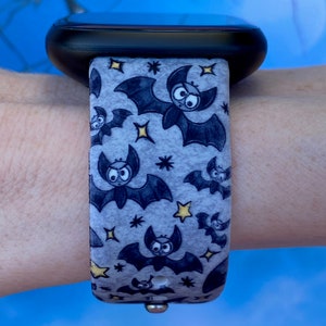 Puede incluir: Una correa de reloj con estampado gris y negro con un dise&ntilde;o de murci&eacute;lagos y estrellas. La correa est&aacute; hecha de un material suave y flexible y es compatible con los relojes inteligentes.
