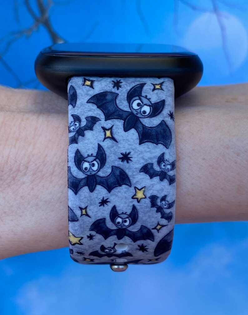 Puede incluir: Una correa de reloj con estampado gris y negro con un dise&ntilde;o de murci&eacute;lagos y estrellas. La correa est&aacute; hecha de un material suave y flexible y es compatible con los relojes inteligentes.