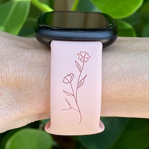 May include: A pink silicone watch band with a floral design. The band is compatible with smartwatches.