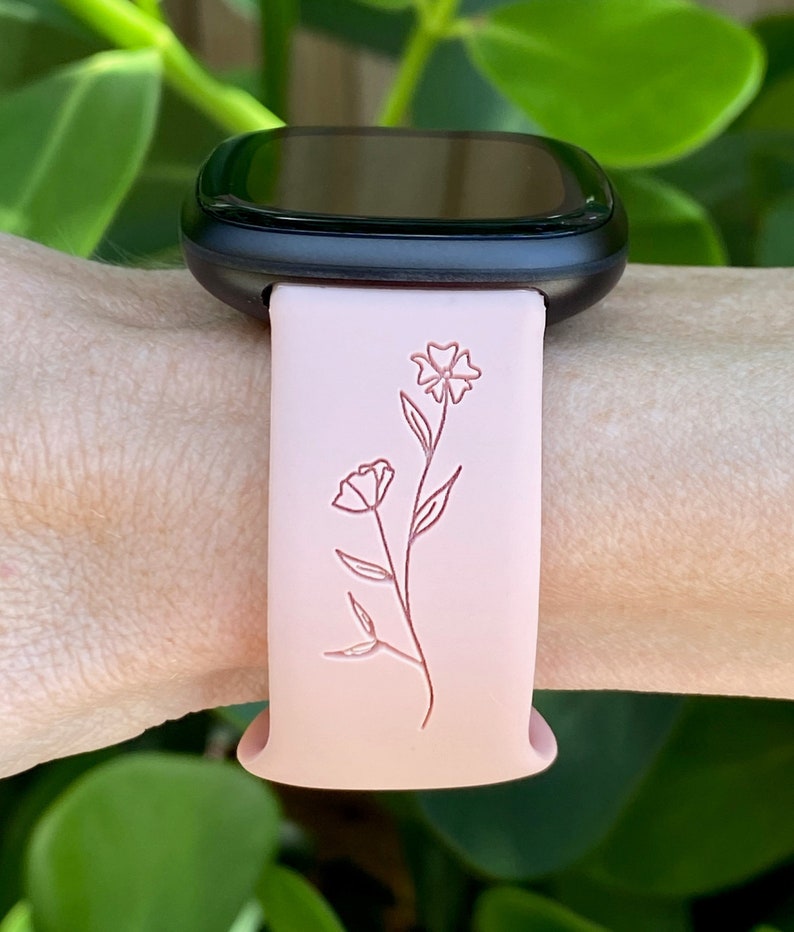 May include: A pink silicone watch band with a floral design. The band is compatible with smartwatches.