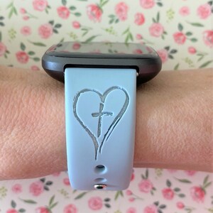 May include: A light blue silicone watch strap with a heart and cross design.