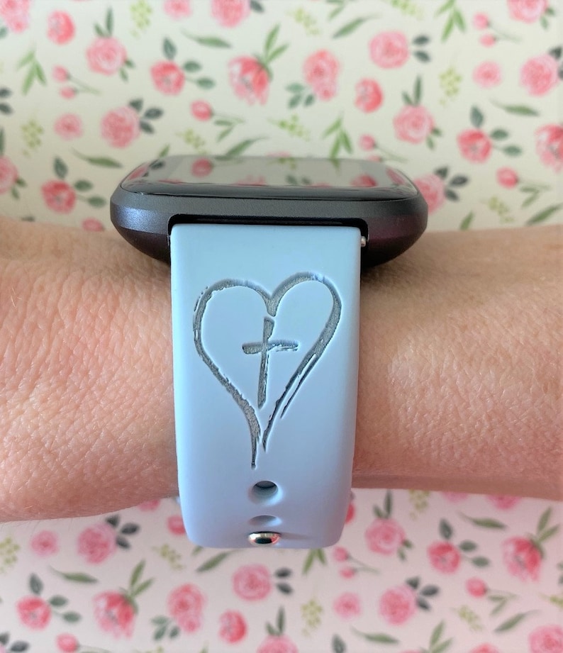 May include: A light blue silicone watch strap with a heart and cross design.
