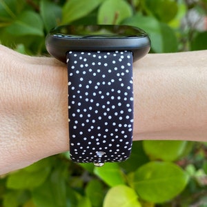 Pu&ograve; includere: Un orologio intelligente nero con un cinturino a pois bianchi. Il cinturino &egrave; in silicone e offre una vestibilit&agrave; comoda.