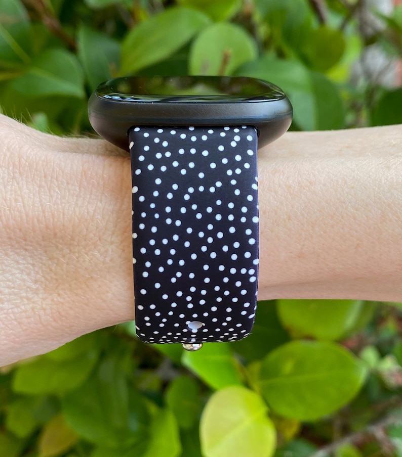 Pu&ograve; includere: Un orologio intelligente nero con un cinturino a pois bianchi. Il cinturino &egrave; in silicone e offre una vestibilit&agrave; comoda.