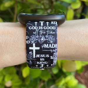 May include: Black and white watch band with a repeating pattern of crosses, flowers, and the text "God is good", "Made new", "Jesus is King", and "God is good".