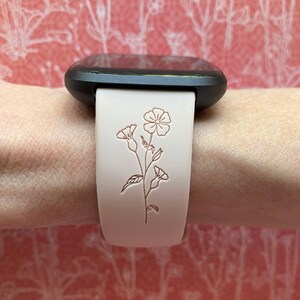 Op de afbeelding: Een wit leren horlogebandje met een bloemenpatroon. Het bandje is voor een vierkant smartwatch.