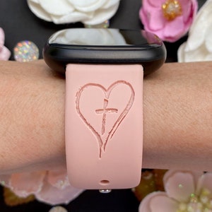 May include: A pink silicone watch band with a heart and cross design.