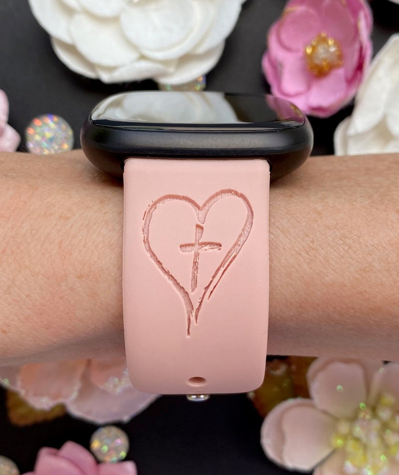 May include: A pink silicone watch band with a heart and cross design.