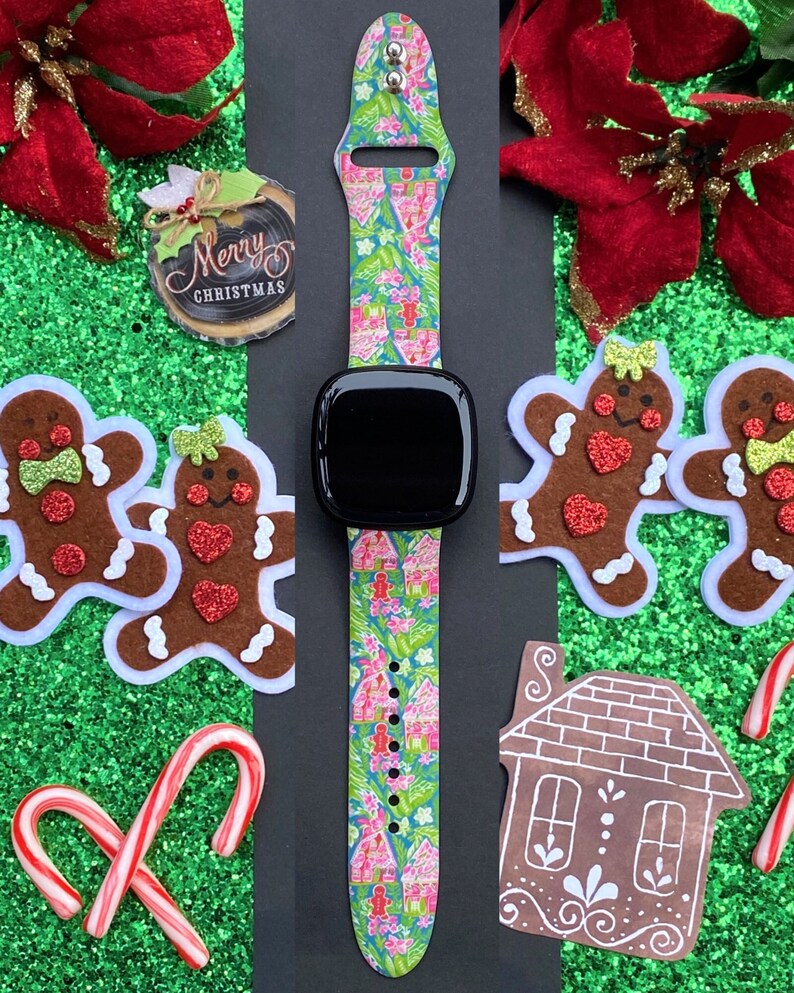 Op de afbeelding: Een kleurrijk kerstthema-horlogebandje met een gingerbreadhuis-patroon. Het bandje is gemaakt van siliconen en compatibel met de meeste smartwatches. Het bandje wordt getoond op een zwarte achtergrond met gingerbreadkoekjes en pepermuntstokken.