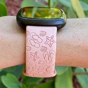 May include: A pink silicone watch band with a beach-themed design. The band features flip flops, seashells, and starfish.