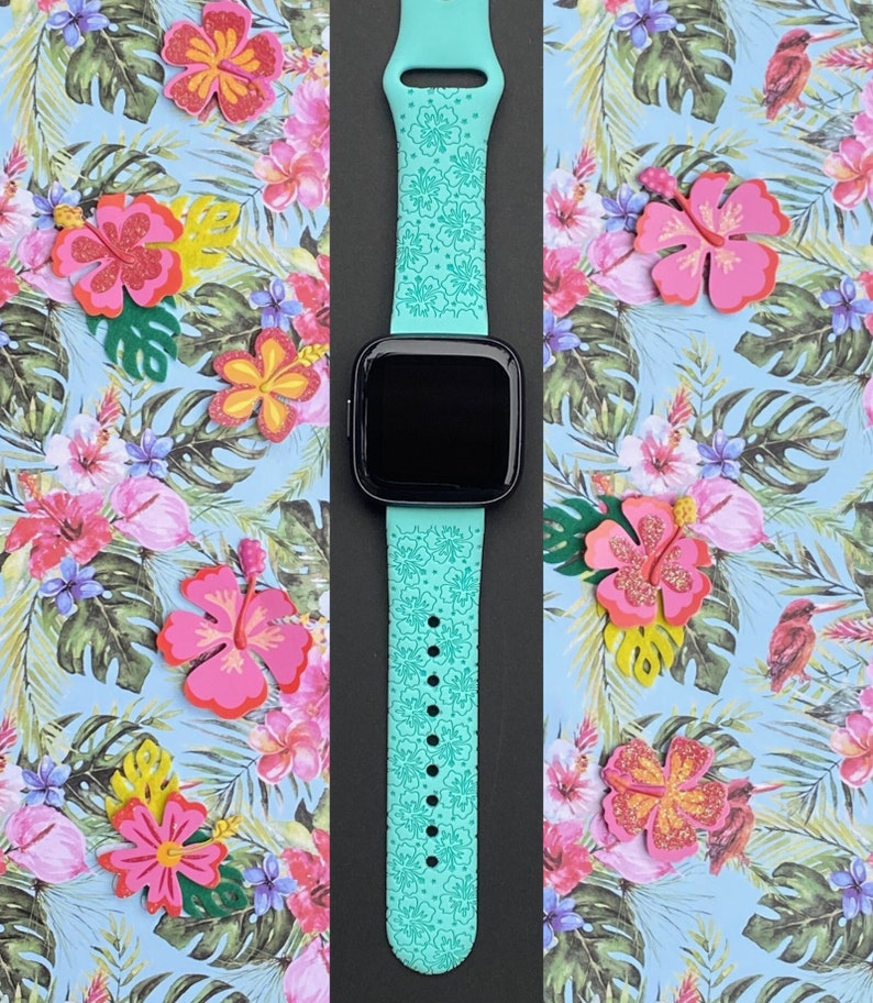 May include: A turquoise silicone watch band with a floral pattern. The band is designed for a smartwatch and has a black screen.