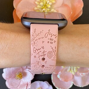 May include: A pink silicone watch band with a floral design and the text "Jesus I trust in you" and "Grow in Faith".