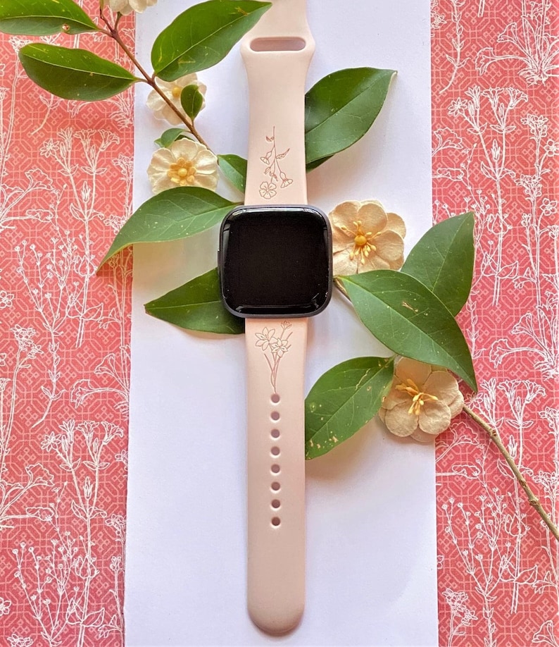 Op de afbeelding: Een roze siliconen horlogeband met een bloemenpatroon. De band is compatibel met een smartwatch en heeft een zwart scherm.