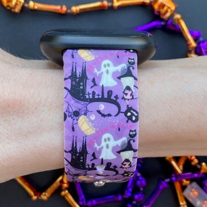 May include: Purple and black patterned watch band with a ghost, witch, and bats. The band says "Happy Halloween".