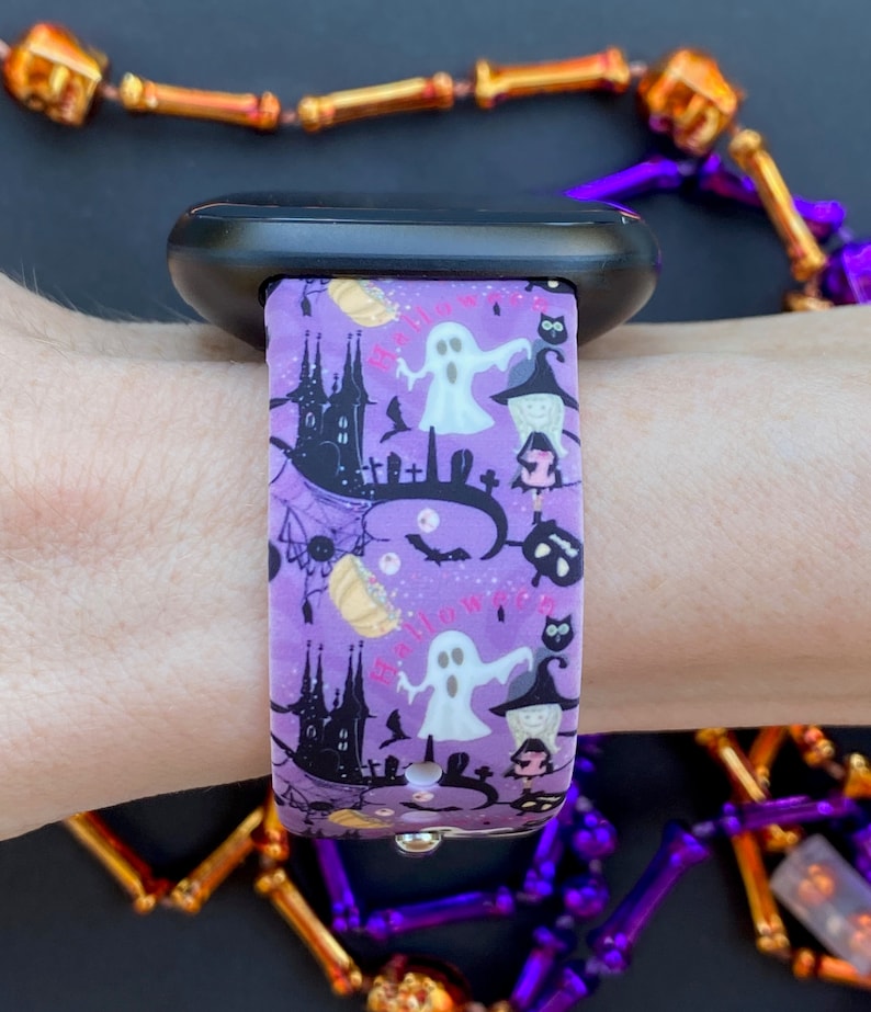 May include: Purple and black patterned watch band with a ghost, witch, and bats. The band says "Happy Halloween".