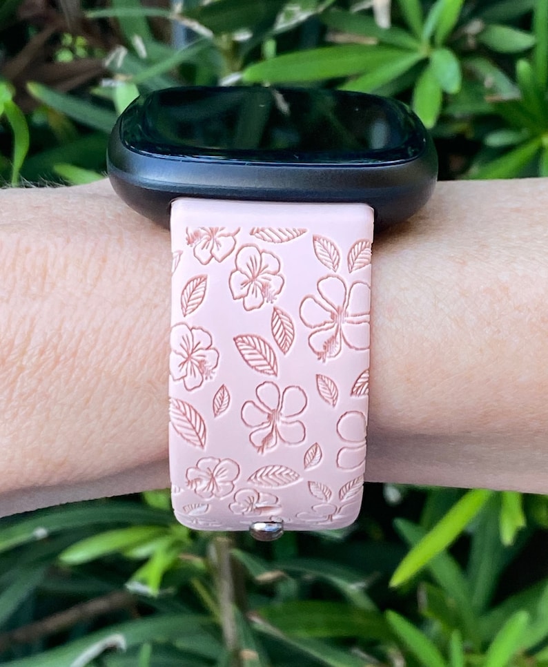 May include: A pink silicone watch band with a floral pattern. The band has a white background with pink flowers and leaves.