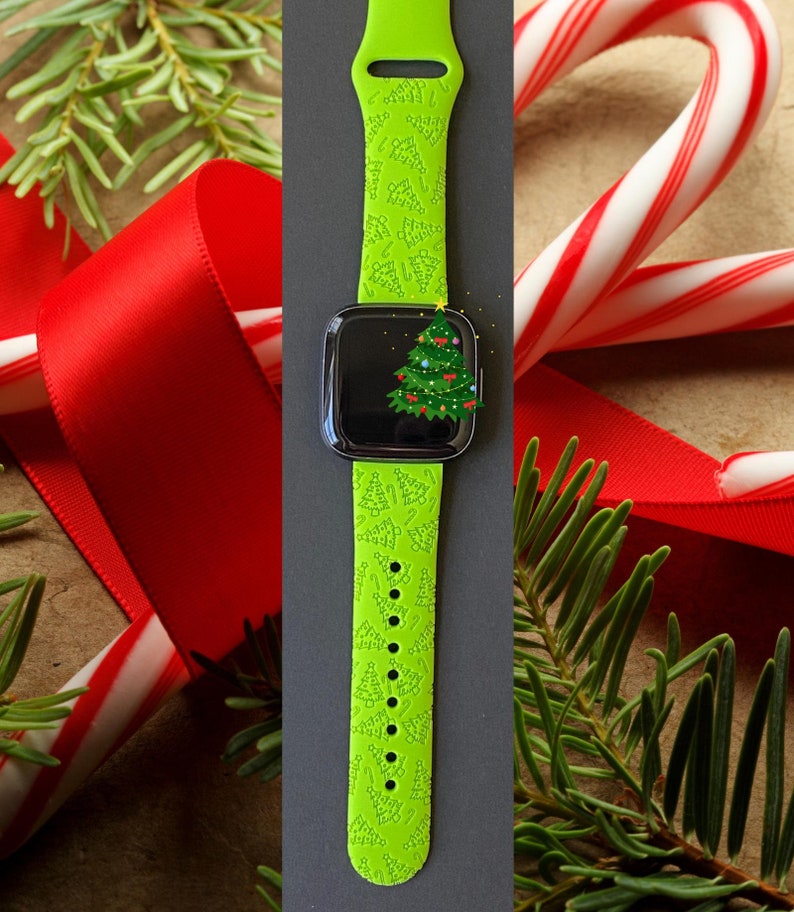 May include: A bright green smartwatch strap featuring a Christmas tree design. The watch face shows a decorated Christmas tree. The image is set against a backdrop of red ribbon, candy canes, and pine branches, creating a festive holiday theme.
