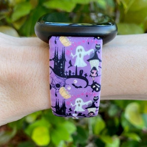 May include: Purple silicone watch band with a Halloween-themed print featuring ghosts, bats, pumpkins, and a castle. The print also includes the word "Halloween" in pink.