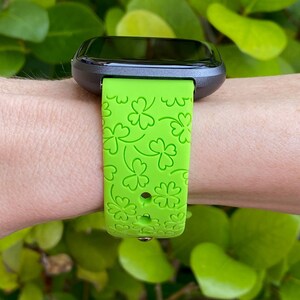 May include: A green silicone watch band with a four-leaf clover pattern.