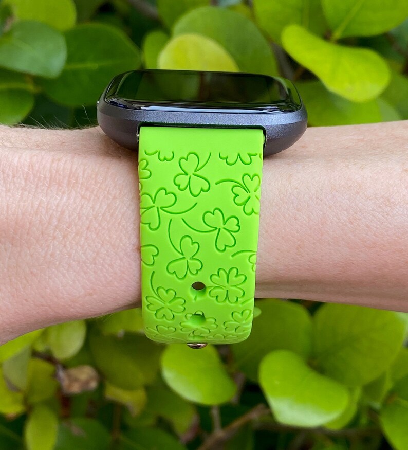 May include: A green silicone watch band with a four-leaf clover pattern.