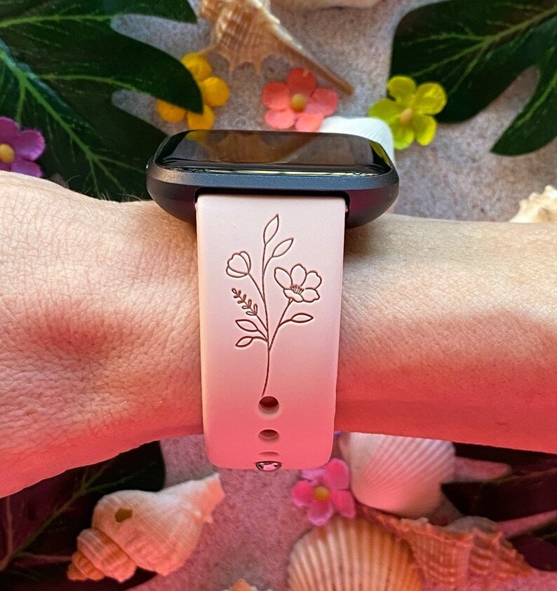 May include: A pink silicone watch band with a delicate floral design. The band is compatible with a smartwatch.