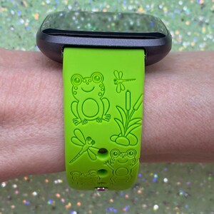 May include: Green silicone watch band with a frog, dragonfly and reeds design.