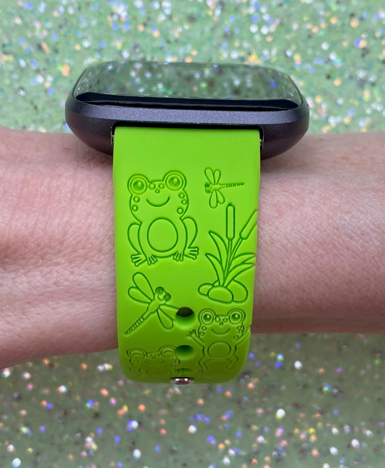 May include: Green silicone watch band with a frog, dragonfly and reeds design.