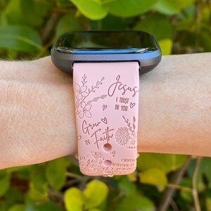 May include: Pink silicone watch band with a floral design and the text "Jesus I trust in you" and "Grow in Faith".