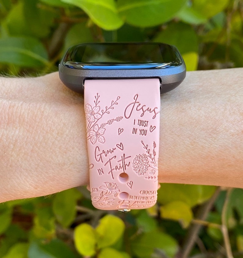 May include: Pink silicone watch band with a floral design and the text "Jesus I trust in you" and "Grow in Faith".