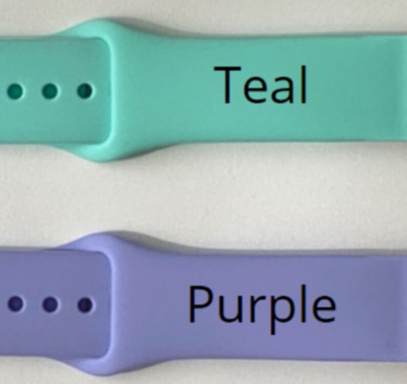May include: Two silicone watch bands in teal and purple. The teal band has the word "Teal" printed on it, and the purple band has the word "Purple" printed on it. Each band has multiple holes for adjustment.