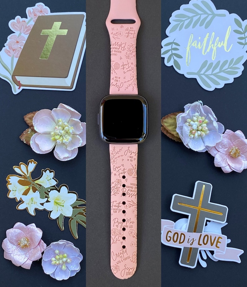 May include: A pink Apple Watch band with a floral design and inspirational quotes, including "Jesus Loves You", "Grow in Faith", "Created with a Purpose", and "Pray More Worry Less".