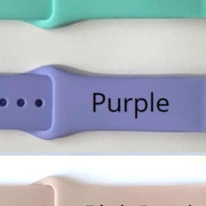 May include: Three watch bands in teal, purple, and pink sand. Each band has a rectangular shape with rounded edges and three holes for adjustment. The colors are labeled with the corresponding color names in black text.