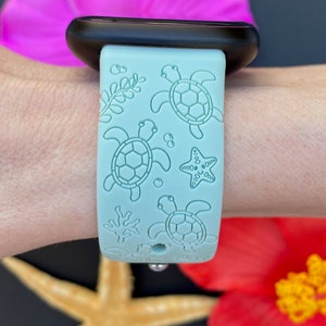 May include: A light blue silicone Apple Watch band with a sea turtle and starfish design.